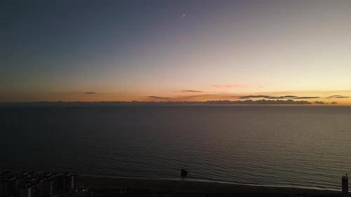 Moon and orange sunset sky over sea horizon, aerial view