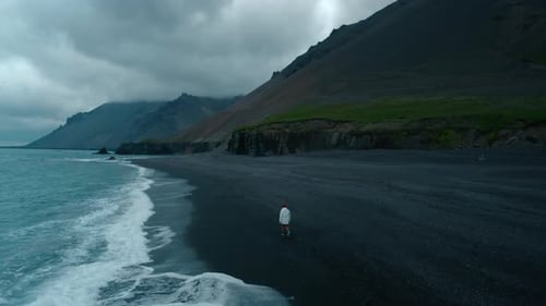 Man Walk on Empty Moody Black Sand Beach