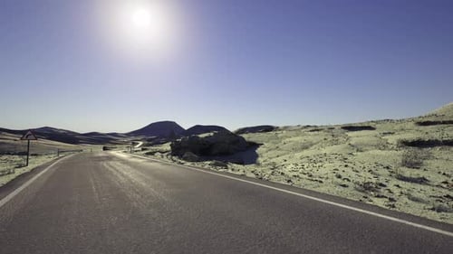 Wide Asphalt Pathway Disappearing Into Clear Sky and Mountain Range