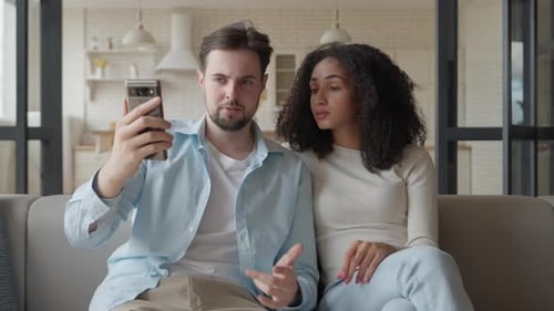 Couple Using Cell Phone on Couch Together