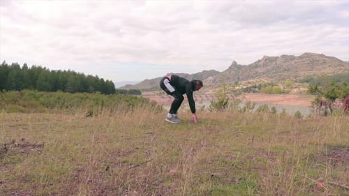 Man training in nature. Work out on a meadow. Fit athlete exercising outdoors.