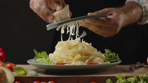 Adding Grated Cheese to Delicious Pasta Dish