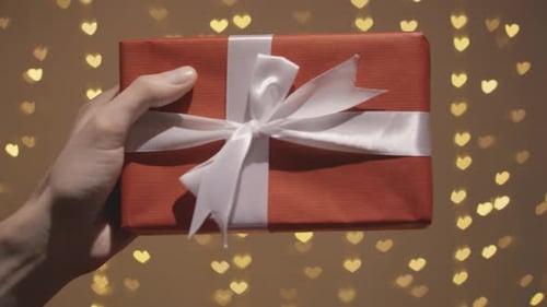 Holding a Red Gift with Heart Lights Background