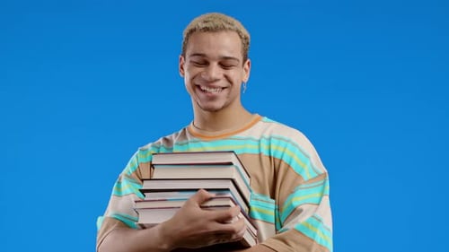 Happy Clever Student Man Holds University Books From College Library on Blue Background
