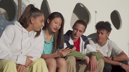 Happy Teenage Friends Looking the Cellphone and Laughing in the City Street