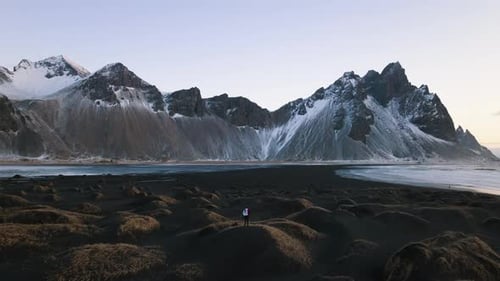 Lone Figure on Black Sand Beach with Mountains