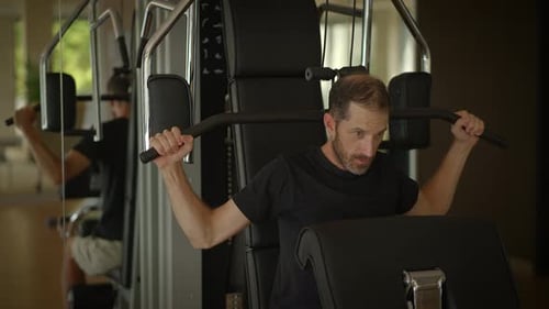 A Man Working Out at the Gym Using Strength Training Equipment for His Fitness and Wellbeing