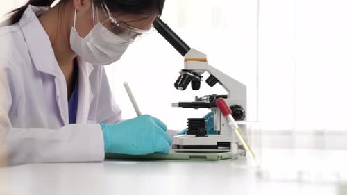 Woman Scientist Works with Microscope in Laboratory