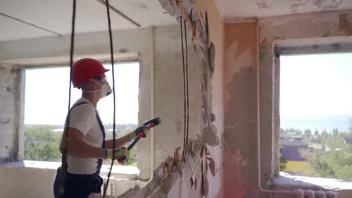 Un contratista destruye una pared con un mazo haciendo un agujero para reorganizarlo