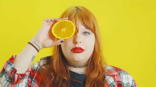 Young Woman Holds Sliced Orange in Front of Face