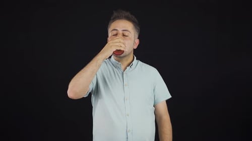 Man Dressed Casually Drinks From a Glass