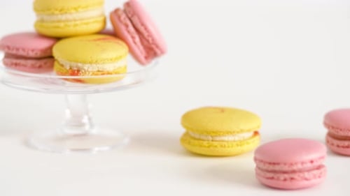 Delicious pink and yellow macarons on white surface