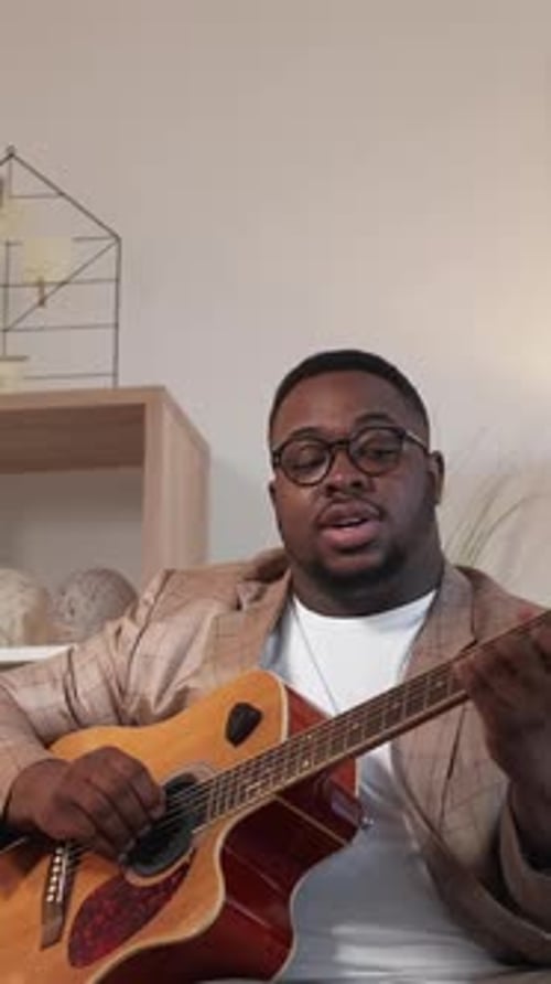 Young Man Singing and Playing Guitar Indoors