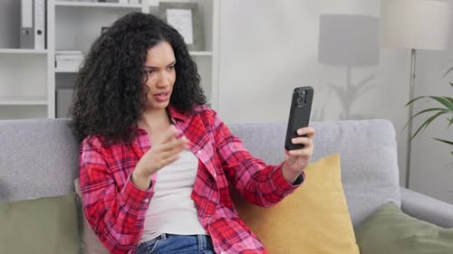 Woman Talks on Phone While Sitting on Couch