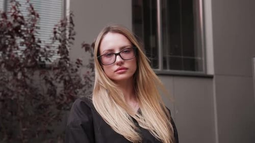 Portrait of Young Attractive Look at the Camera at Urban City with Long Blond Hair and Glasses Wind