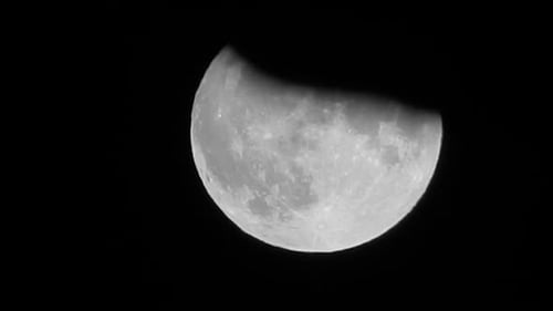 Massive full orange harvest moon crater surface closeup passing rooftop silhouette skyline