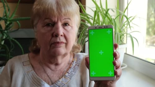Elderly Woman Shows Green Screen Mobile Phone Close Up in Vertical Position