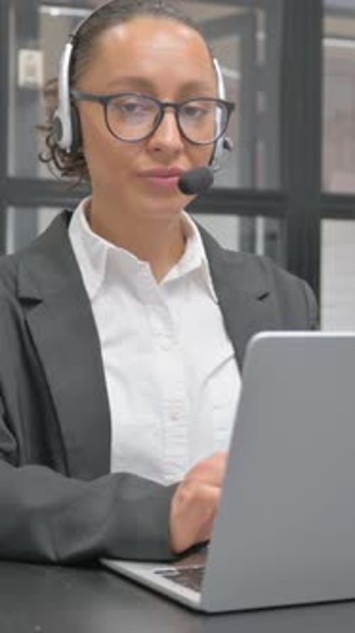 Woman with Headset Working on Laptop at Desk
