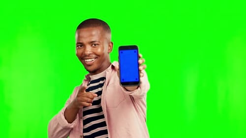 Happy black man, pointing and phone mockup on green screen for advertising against a studio