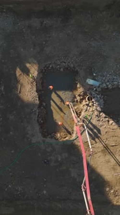 Vertikales Video: Erfahrene Bauarbeiter und Maschinen, die an der Fundamentvorbereitung arbeiten