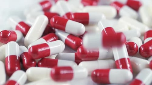 Capsule on a White Background Filled with Medicine is in a Chaotic Order Pills Fall on the Table