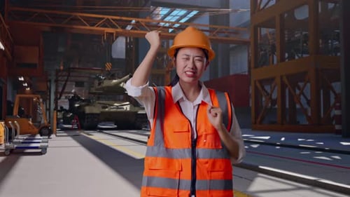 Une ingénieure asiatique danse en train de célébrer, un char en construction