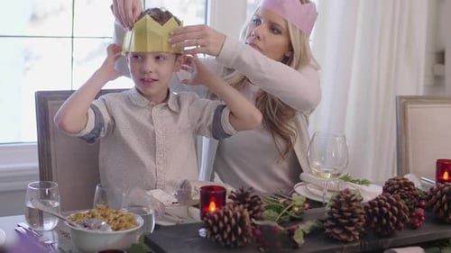 Family enjoying christmas crackers and party hats in Canada