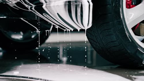 Close-up of car wash detergent dripping off a luxury car during a car cleaning or car wash