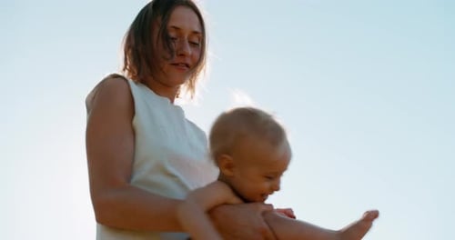 Mains de maman tenant un petit fils mignon et heureux qui tourne ensemble à la campagne
