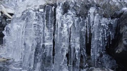 Wide and close tilt shot of a little frozen waterfall. Nice icicles.