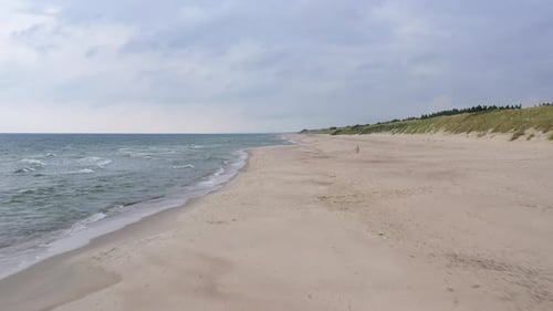 LUFTBILD: Vorwärts fliegen an einem bewölkten Abend über Sandstrand und Meeresküste