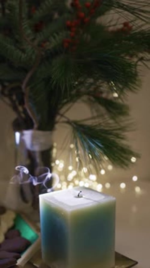 Burning candle close-up. Decorated christmas tree on background. Winter holidays concept. Celebratin
