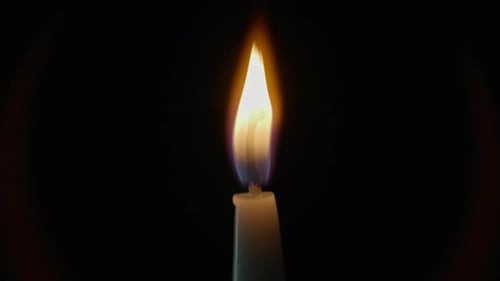 Closeup Candle Flame Glowing Atop Wax Standing Tall on Dark Studio Background