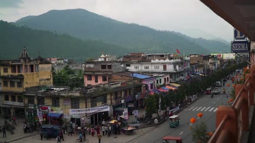 Panning shot of a busy street in a Nepalees city on a cloudy day.