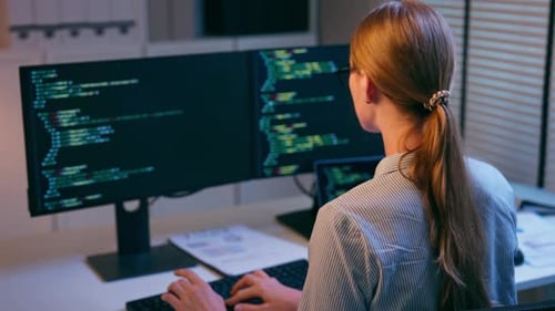 Caucasian young female software engineer working at night in the office.