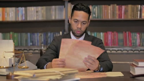 Man in Suit Looking at Paper Documents