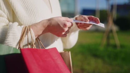 Woman Checks Receipt Outside Shopping With Bags