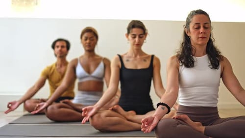 Group Meditating in Lotus Position in Yoga Studio