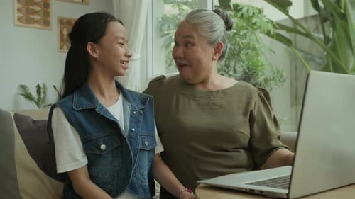 Teen Girl Teaching Grandmother How to Use Laptop