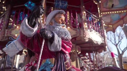 Christmas statue of Santa Claus on a merry-go-round, colourful carousel on a sunny day