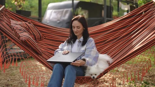 Woman Relaxes with Dog in Hammock