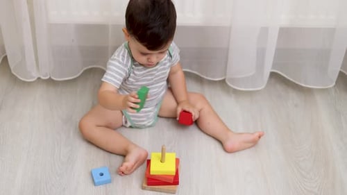 adorable baby boy child playing at home floor with wooden building block set,pyramid puzzle,