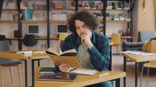 Young Man Student Reading a Book in the Library or Classroom Interested Reading a Book Student in a