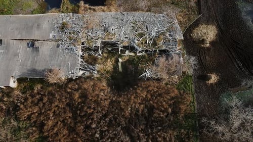 Aerial shot of the destroyed cattle barn and explosion crater, real war in Ukraine