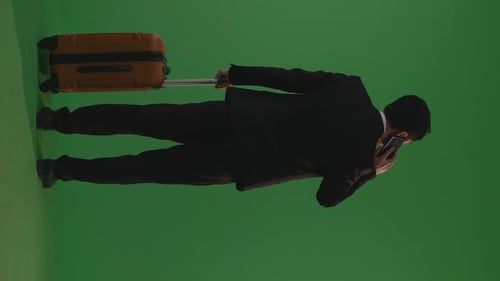 Back View Asian Businessman With Luggage Talking On Smartphone While Standing In The Green Screen