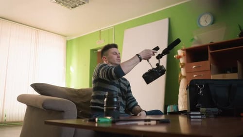 Man Reaches for Camera Gear in Home Studio Organizing Equipment in Black Bag