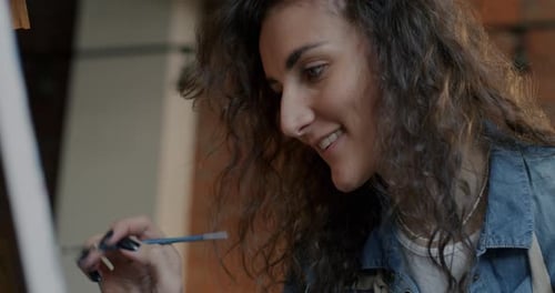 Happy Female Artist Focused on Masterpiece Creation Enjoying Work with Picture in Studio