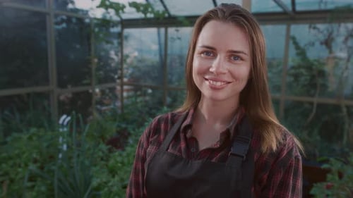 Woman Smiling in Lush Greenhouse Setting