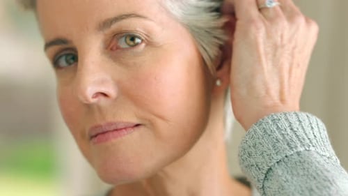Mature Woman Touches Face in Bright Indoor Setting