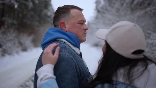 A Woman Hugs Her Husband During a Walk in a Snowy Forest The Concept of Family Vacation